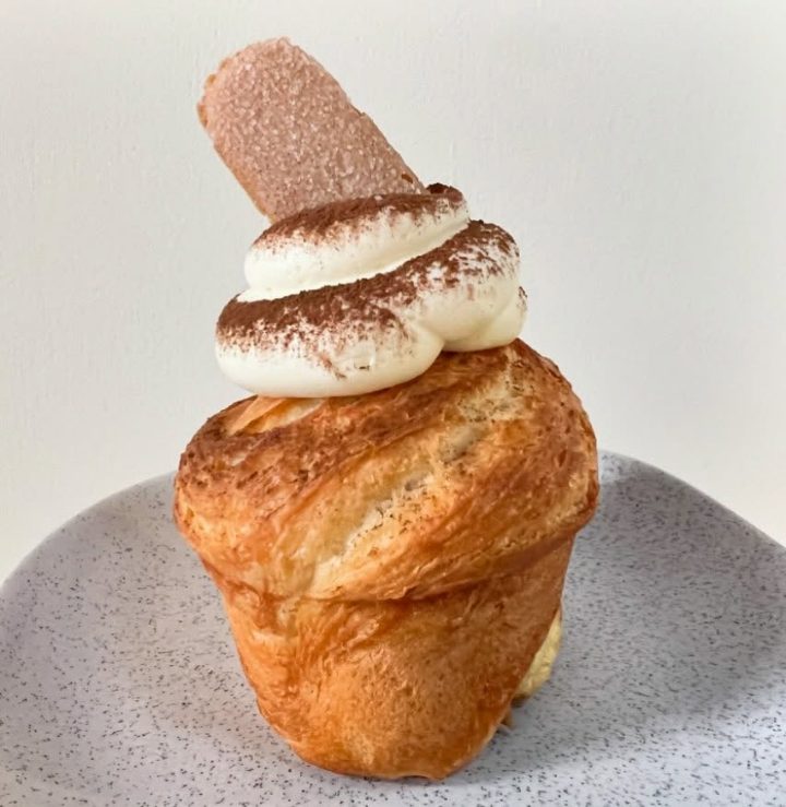 A cruffin: spiralled laminated dough crowned with cream and a biscuit