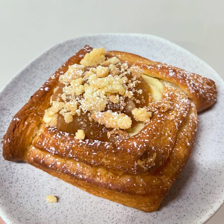 A custard Danish with crumble, glazed and fresh from the oven