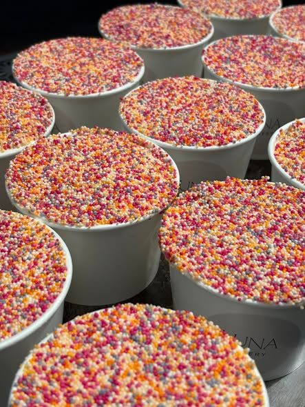 Trays of dot cakes covered edge to edge in rainbow sprinkles