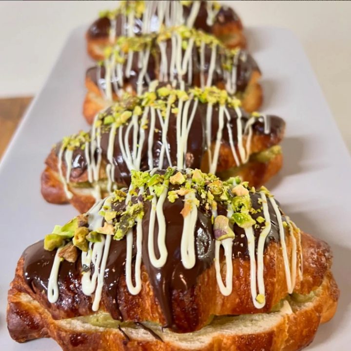 Pistachio chocolate croissants drizzled with white chocolate and crushed pistachios